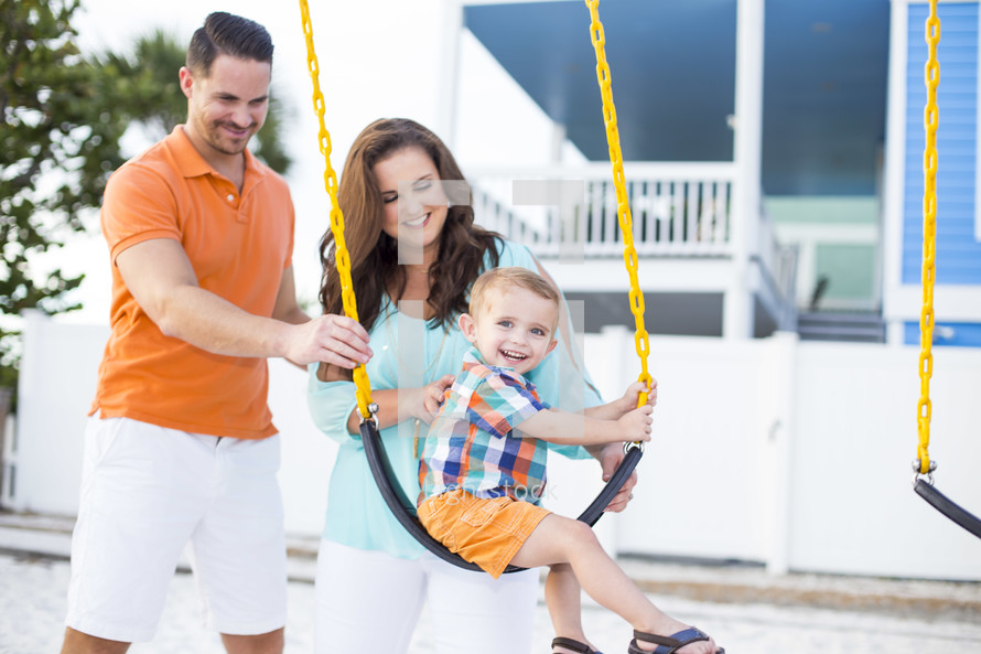 father and mother pushing son on a swing 
