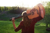 a woman standing outdoors with a guitar 
