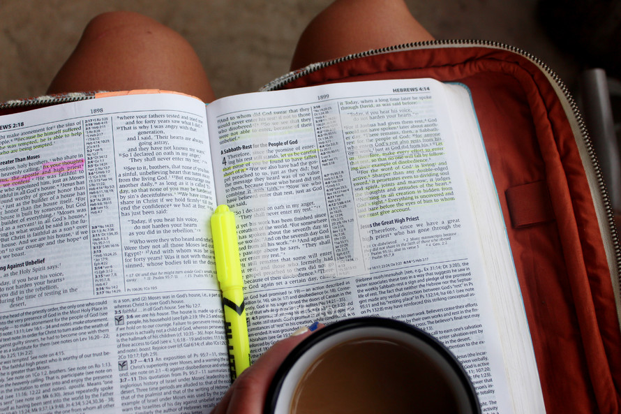 opened Bible in a lap with a mug 
