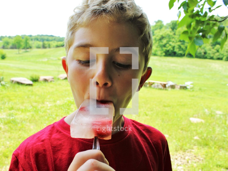 a boy eating a popsicle 