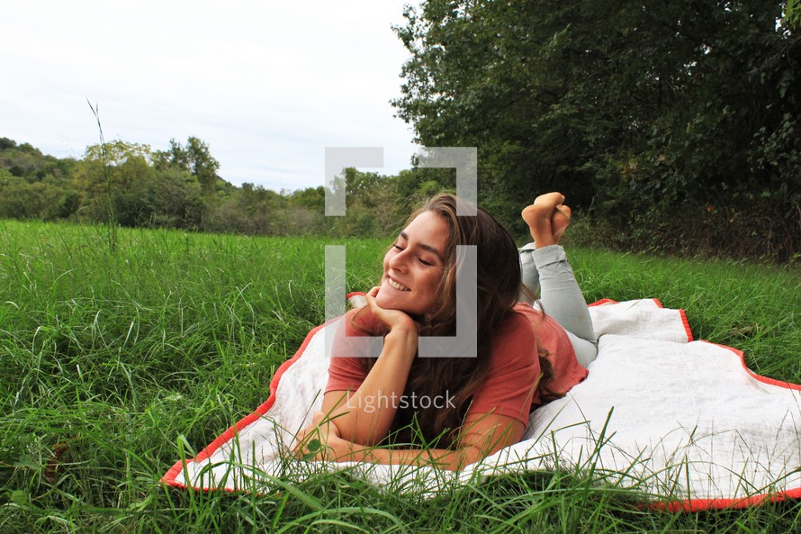 a woman lying on a blanket in the grass