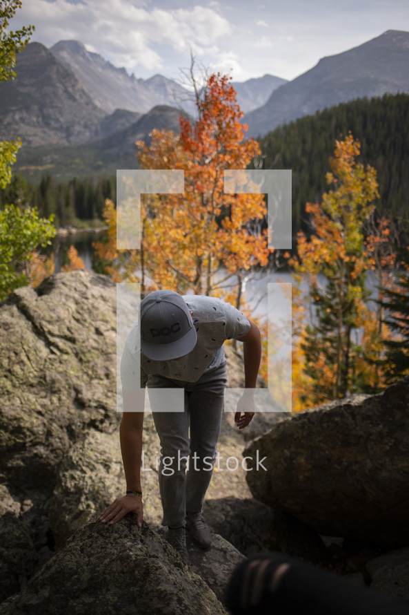 man climbing up rocks in an autumn forest 