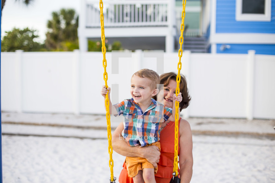 grandmother pushing her grandson on a swing 