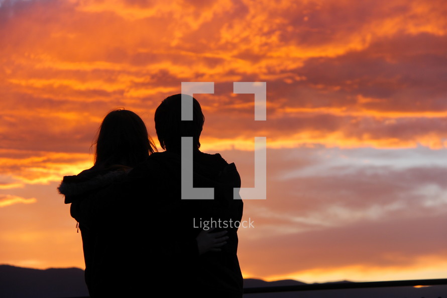 silhouette of a couple under an orange sky at sunset