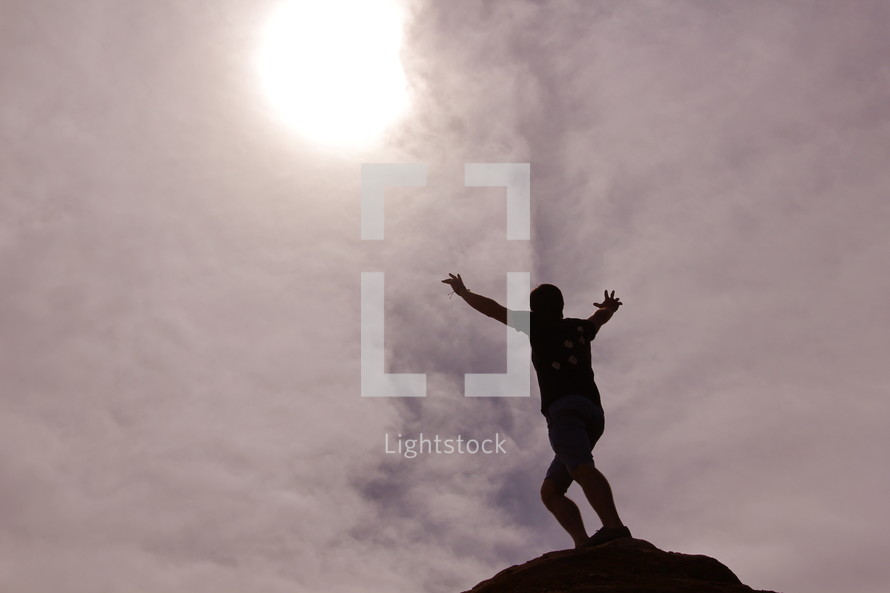 Silhouette of a man with his arms raised on top of a mountain after a hard climb