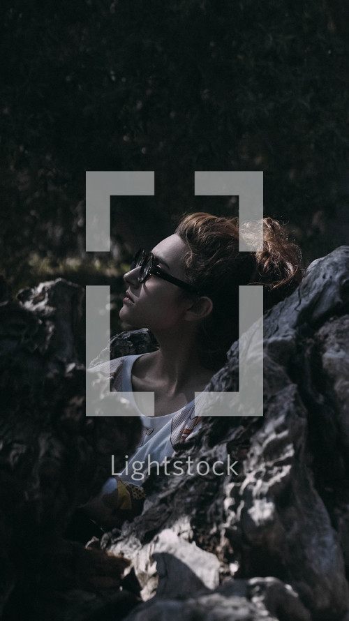 teen girl looking up standing between rocks  