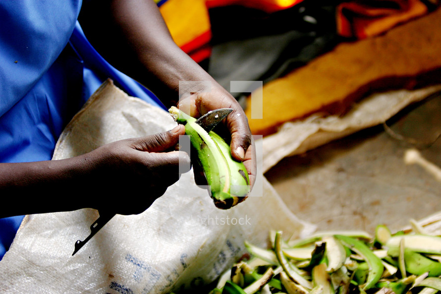 African woman peeling  fruit plantain knife cooking