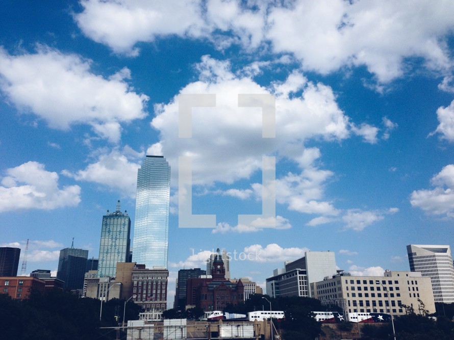 city buildings under white clouds and blue sky