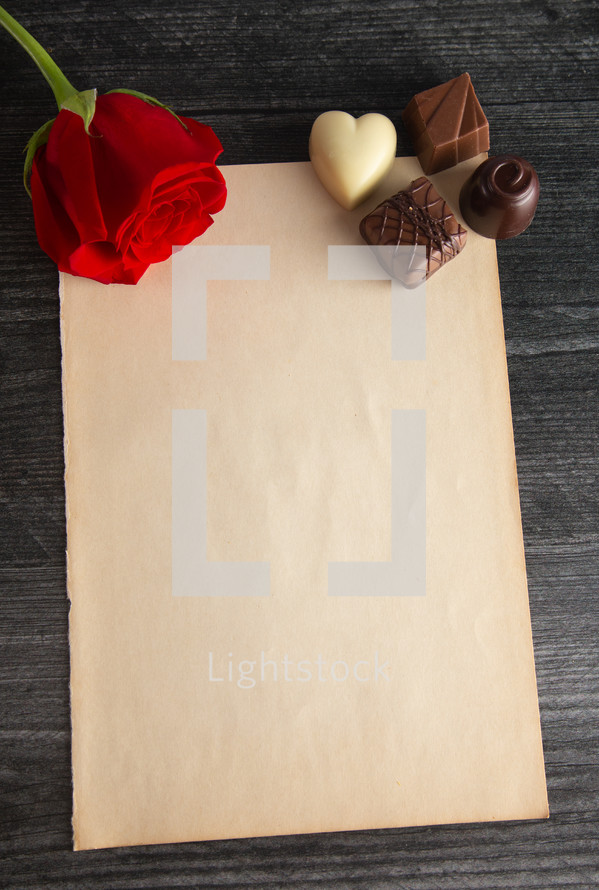 chocolates, red rose, and paper for a love letter 