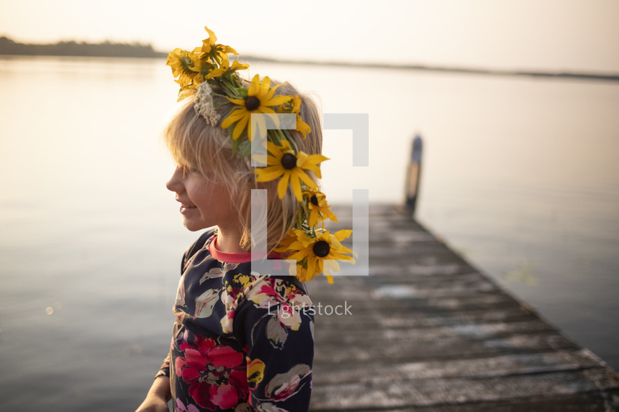 flowers in a girls hair while standing on a dock 