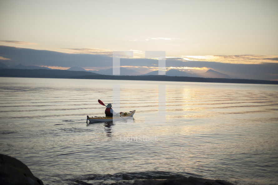 a man rowing a kayak at sunset 