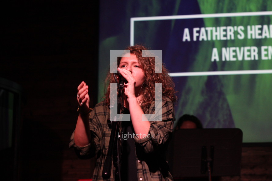 a woman singing into a microphone at a worship service 