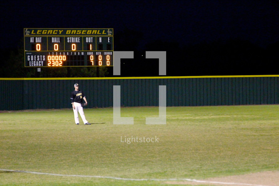 Scoreboard and outfielder at a baseball game.