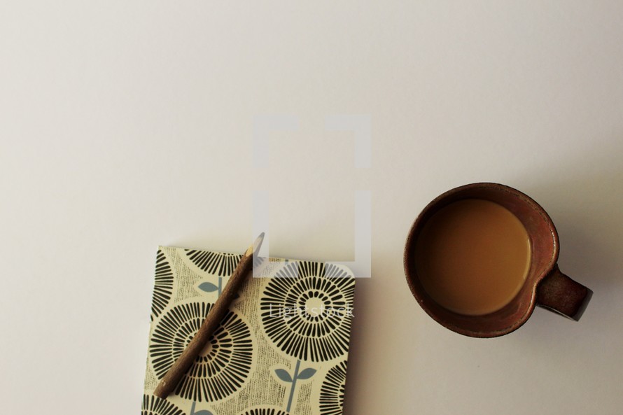 pencil on a journal and a coffee mug