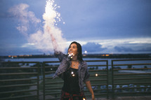woman holding a sparkler under a cloudy sky
