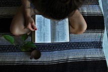 a girl reading a Bible and writing in a notebook 