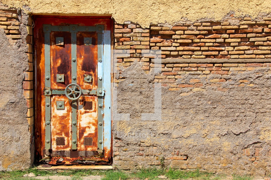 Old rusted vault door in weathered brick wall