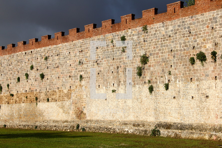 fortress wall and green grass with dark storm clouds behind