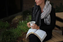 a woman holding a mug with a Bible on her lap 