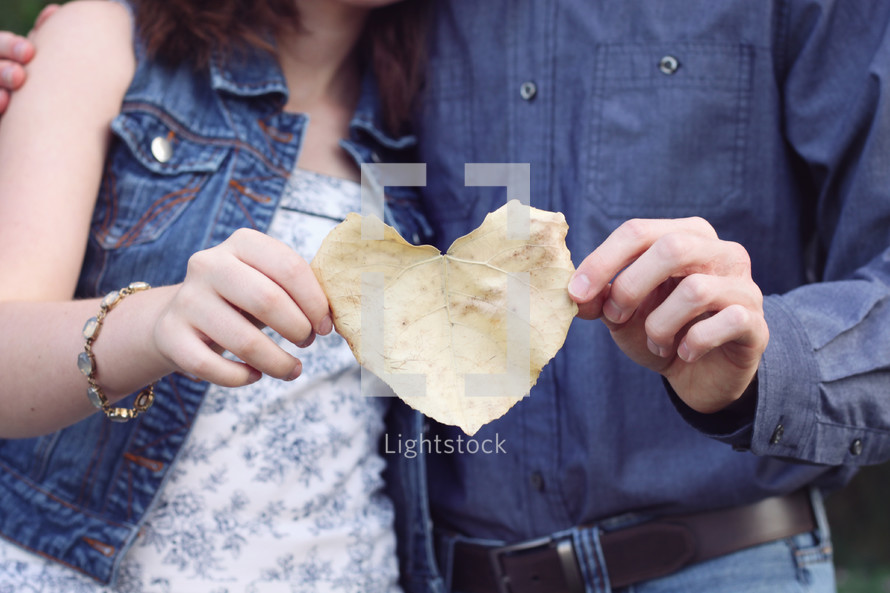 a couple holding a heart shape fall leaf 
