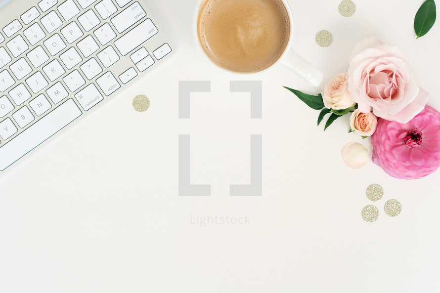 keyboard, coffee mug, glittery dots, and flowers on a desk