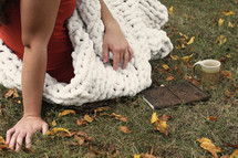 a woman wrapped in a blanket sitting outdoors next to a Bible 