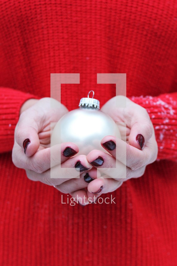 cupped hands holding a Christmas ornament 