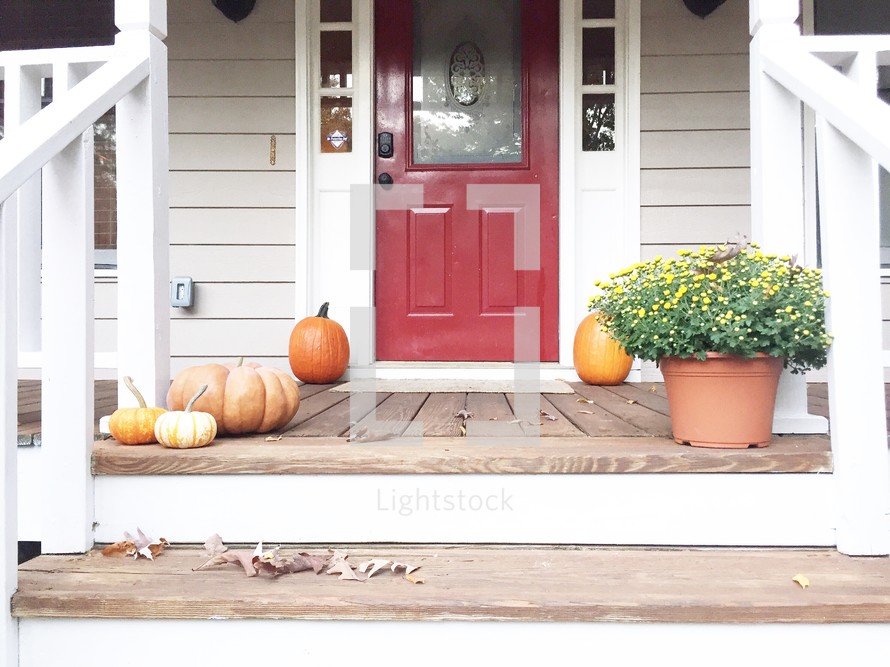 pumpkins and mums on a front porch 