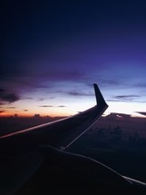 wing of a plane in flight at night 