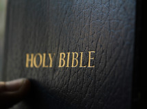 Thumb on black leather cover of Holy Bible.