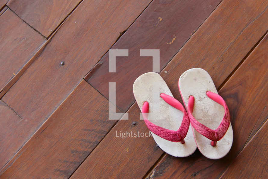 Child's flip flops on a wooden floor.