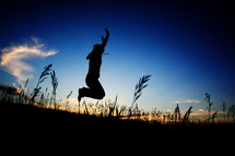 silhouette of a man jumping in a field