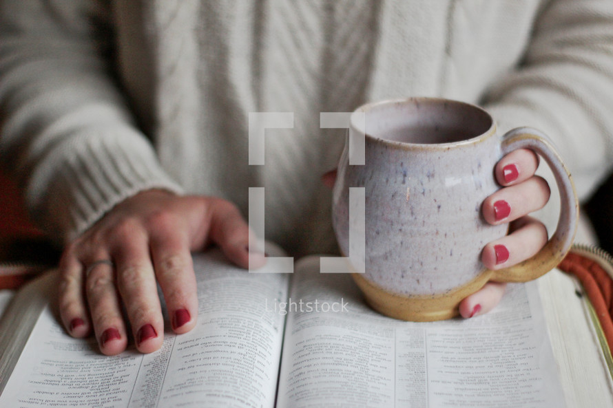 a woman reading a Bible holding a coffee mug 