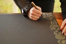 artist drawing a border of gold on black