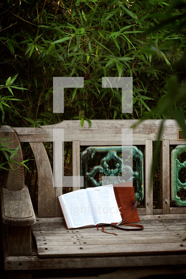 a Bible and journal on a park bench 