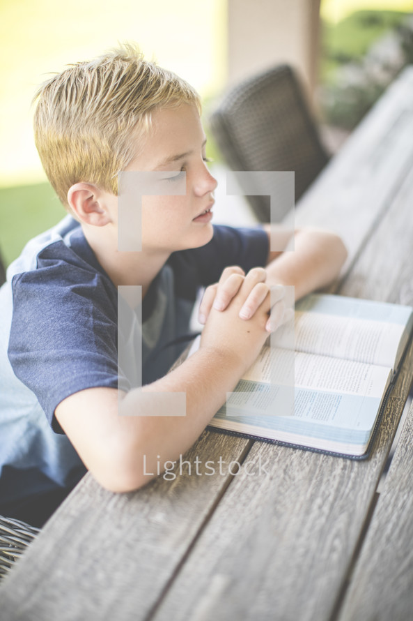 a boy reading a Bible and praying 