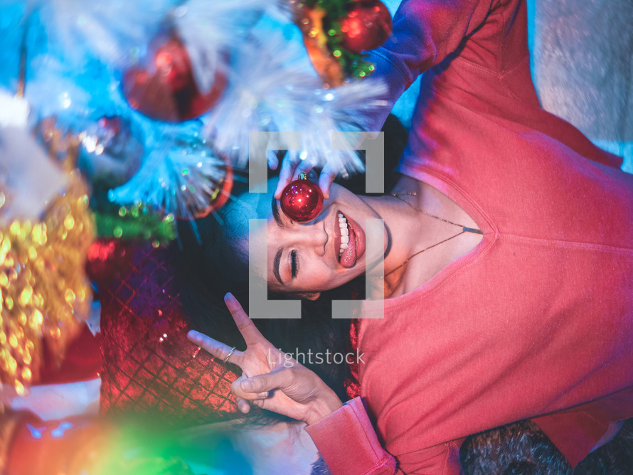 a woman making a silly face holding Christmas decorations 