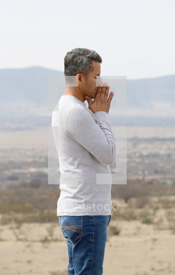 a man in prayer with a desert mountain view 