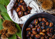 Roasted chestnuts in iron skillet on wooden table.
