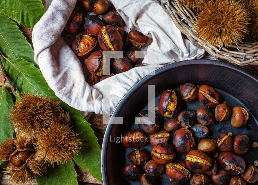 Roasted chestnuts in iron skillet on wooden table.