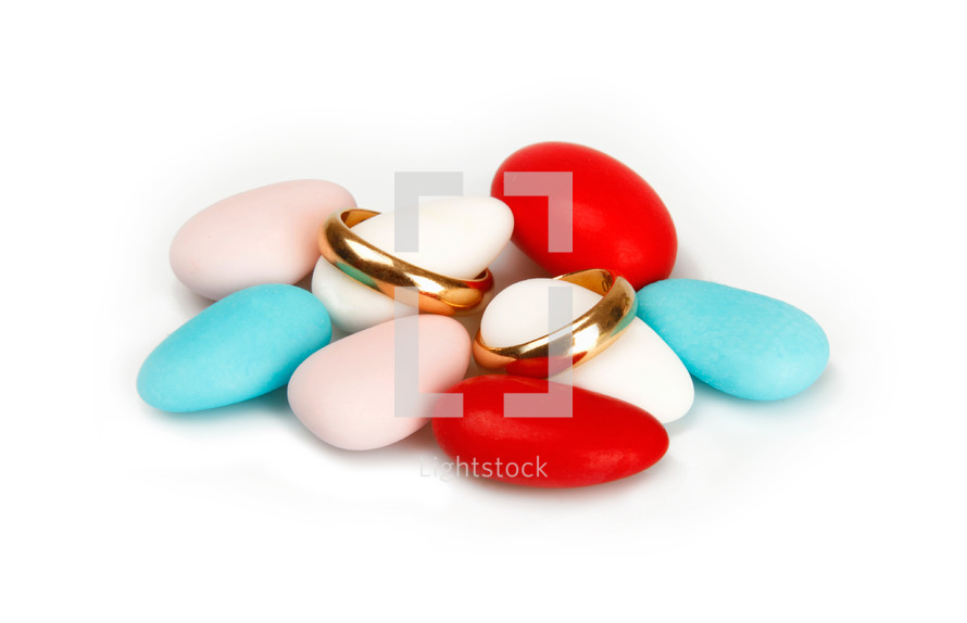 Colorful Confetti with wedding rings on white background.
