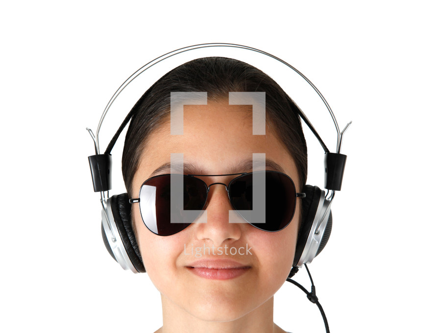 Young girl with sunglasses while listening music with headphones on white background