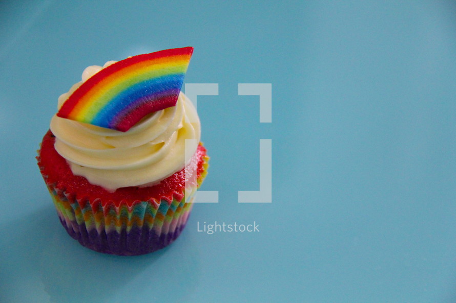 Cupcake decorated with cream cheese and a fondant rainbow