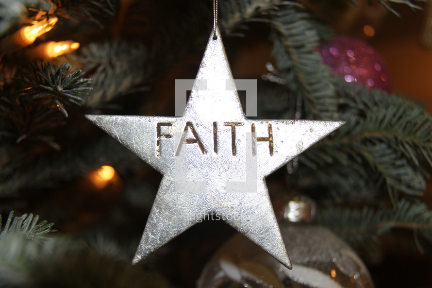 Star ornament with the word Faith hanging on a Christmas tree 