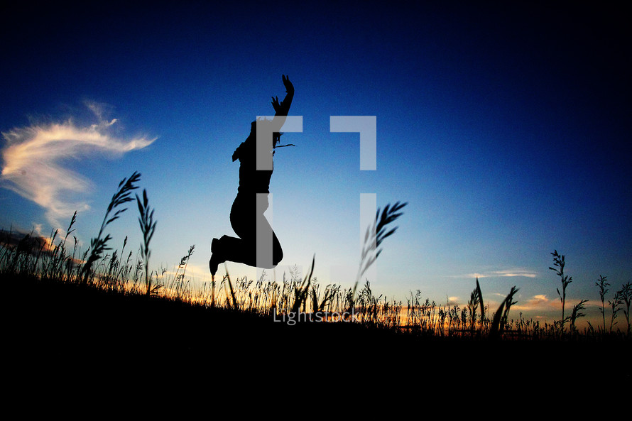 silhouette of a man jumping in a field