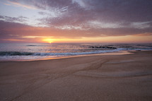 tide washing onto a beach at sunrise 