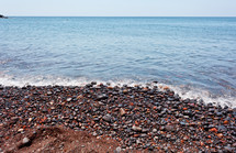 Red pebbles of the typical red beach of Santorini, Greece.