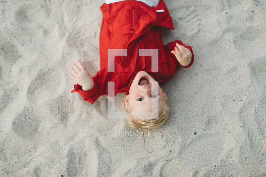 toddler lying in sand on a beach 
