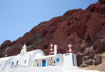 Traditional chapel with Greece flag in red beach, Santorini