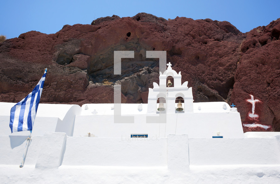 Traditional church with Greece flag in red beach, Santorini